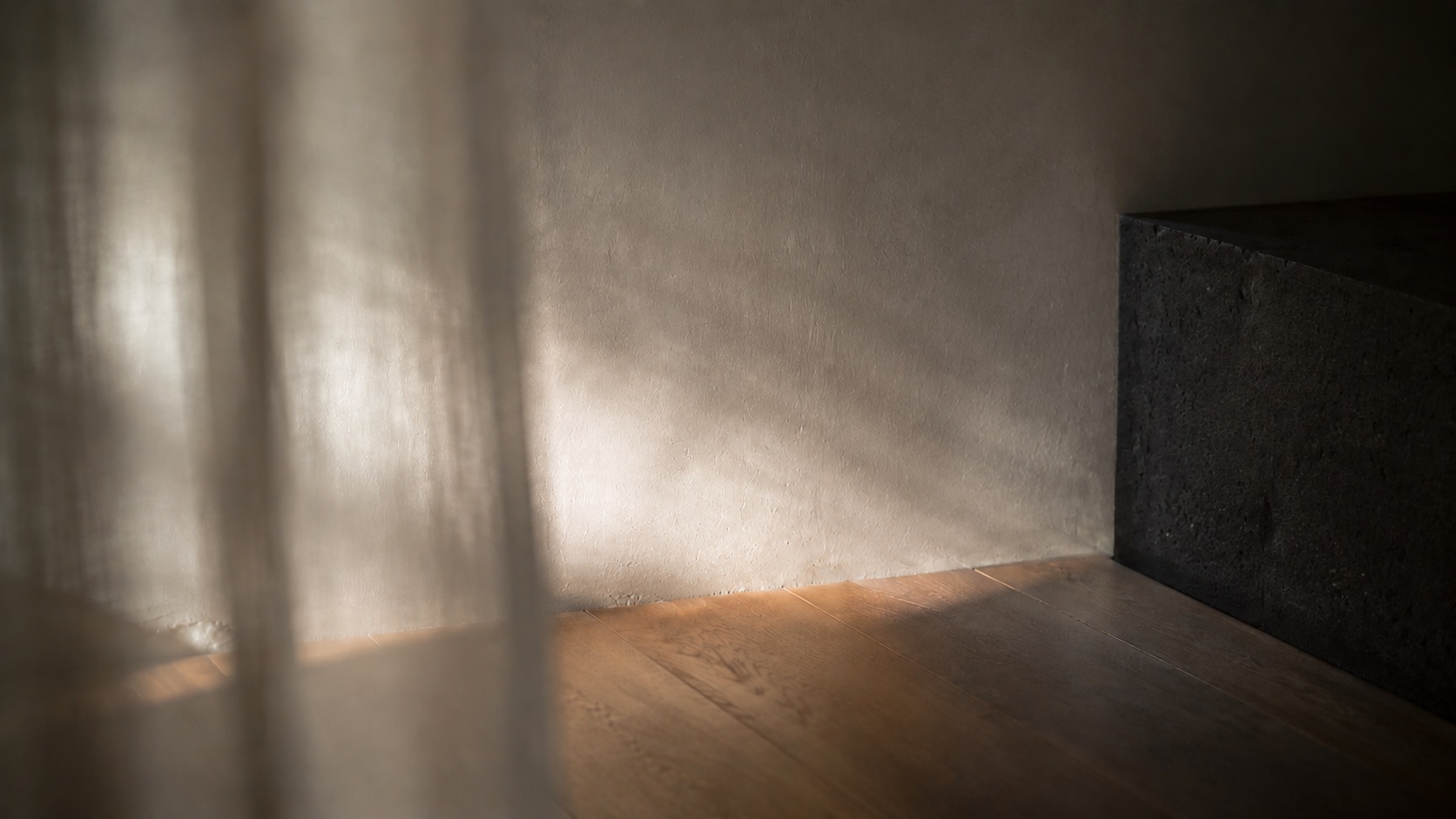 Luz oblicua sobre pared cálida y suelo de madera